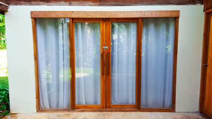 Double glass doors with wooden frames and white curtains behind