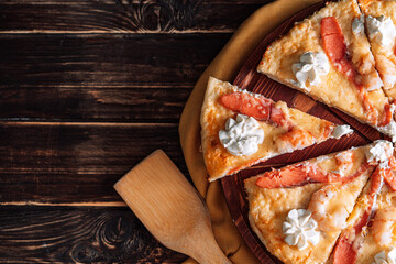 Seafood pizza cut into equal pieces on wooden tray with wooden spoon