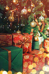 Many gift boxes with sequins standing under a decorated Christmas tree