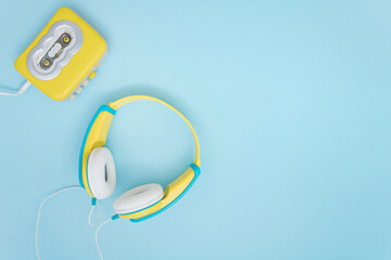 Retro Walkman in yellow color on blue background with cool  headphones. - obrazy, fototapety, plakaty