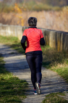 Elderly Woman Running To Stay Healthy, Seen From Behind.