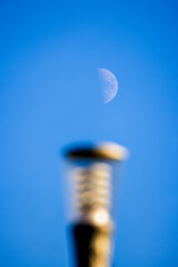 landscape with the moon in focus and a blurred street light in front.