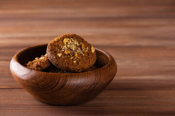 Homemade oatmeal cookies with nuts in a wooden bowl. Sugar, gluten, lactose free, vegan. Horizontal orientation, copy space.