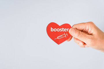 senior  hand holding red heart paper shape with booster word and syringe icon for vaccinated or...