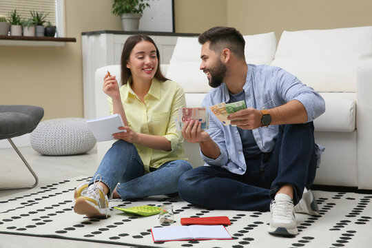 Happy couple counting money on floor at home