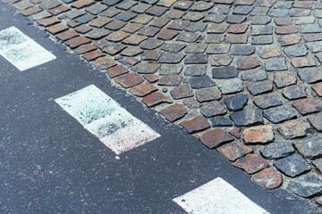 Paving stones pathway and asphalt with markings texture. Cobblestone and asphalt background