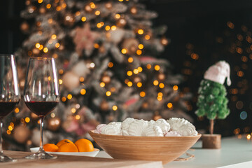 Two glasses, tangerines, marshmallows and decor on the background of the Christmas tree, New Year