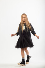 A full-length portrait of dancing young girl with long brown hair dressed in a hooligan style.