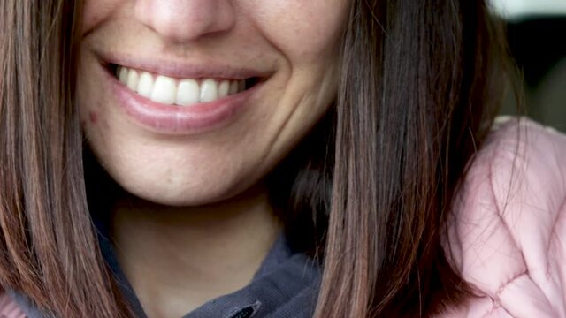 close up of woman smiling. big front teeth. natural look of the skin. big lips, no makeup.
brunette girl, straight medium hair. happiness. one front tooth is bigger and irregular than another.