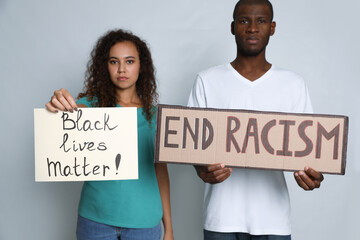 African American woman and man holding signs on grey background. Racism concept
