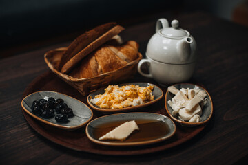 Traditional Turkish breakfast with fried egg, black olives, croissant, bread, cheese, butter in honey and tea on a wooden table. Organic, fresh and tasty food