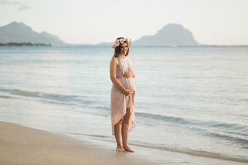 Fototapeta na wymiar Pregnant woman in a beautiful dress on the ocean.