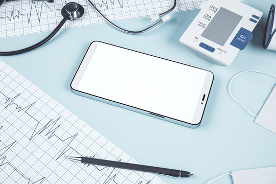 Top view of blue table with blank smart phone, stethoscope, cardiogram, pen, other items and mock up place. Doctor's office, workplace and diagnosis concept. 3D Rendering.
