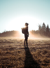 Girl standing in thick fog with a colorful morning sunlight. Human silhouette in different poses in autumn.