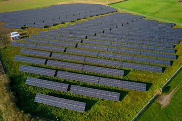 Photovoltaic panels for solar energy. Aerial view of a solar farm on the green field. Solar panels on a row in a sunny day. 