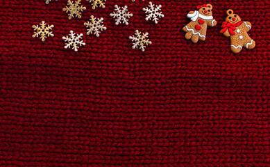 Golden snowflakes, gingerbread men on red knitted background. Winter holidays concept. Christmas décor. Christmas greeting card or New Year card. Top view. Flat lay. Place for text. Copy space.