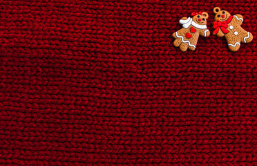 Gingerbread men on red knitted background. Christmas three decorations or New Year decorations. Flat lay. Cope space. Place for text. Top view. Holiday concept. Christmas greeting card.