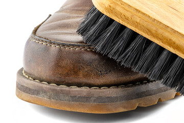 Macro photo of an old brown leather booties polished with paste, shoe brush lies on the shoe,...