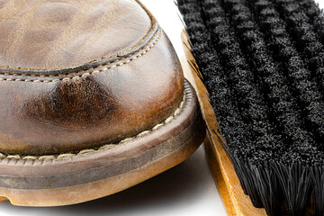Macro photo of an old brown leather booties polished with paste, next to it lies a shoe brush,...