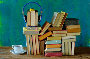 Fototapeta na wymiar audio book concept, with stack of books, headphones and cup of coffee,