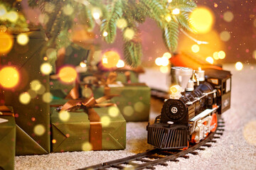 Toy train under Christmas tree with gift boxes