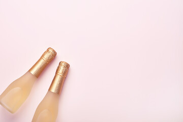 Fototapeta na wymiar Champagne bottle, gift or present box and golden shiny sparkle star confetti on pink background. Christmas or New Year composition or card. Celebration flat lay. Party creative concept. Top view.