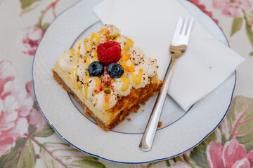 Mille-feuille or milhoja, Portion cake, Puff pastry with vanilla butter cream and whipped cream on white plate with dessert fork, fresh lingonberries and raspberries, selective focus, Castolovice cafe