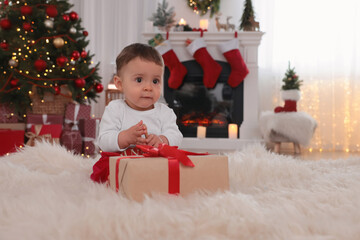 Obraz na płótnie Canvas Baby with toy and gift box on floor in room decorated for Christmas