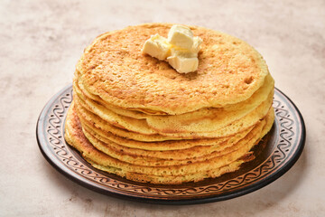 Crepes or thin pancakes stack with butter and red caviar on beautiful ceramic plate on an old brown concrete background. Top view, copy space. Homemade thin crepes for breakfast or dessert.