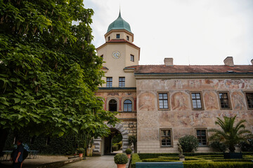 Fototapeta na wymiar Castolovice, Eastern Bohemia, Czech Republic, 11 September 2021: renaissance castle with tower at sunny day, courtyard with arcades and geometric flower beds, murals and sgraffito plaster on walls