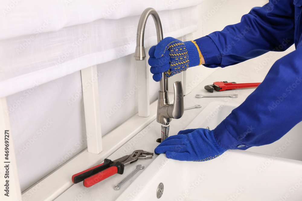 Wall mural Plumber repairing water tap in kitchen, closeup