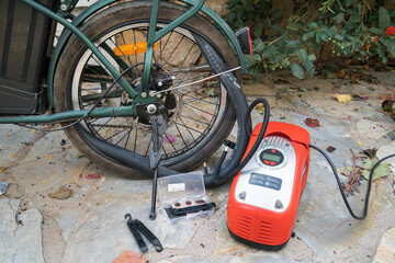 Bicycle wheel, tire repair. Inflating the tire with an electric air pump to find the puncture before patching with the repair kit.