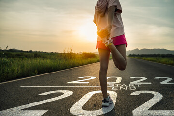 New year 2022 or start straight concept.word 2022 written on the asphalt road and athlete woman...