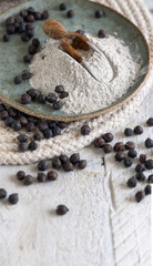 Fototapeta na wymiar Plate and wooden scoop of black chickpea flour and beans closeup