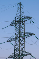 The metal supports of a high-voltage power line against a blue sky. The concept of the energy crisis in Asia and Europe.