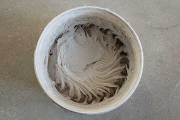 Freshly mixed plaster in a white plastic bucket. The mixture is ready to work. Top view. The concept of room renovation.