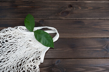eco bag mesh with green leaves on a wooden background. zero waste concept