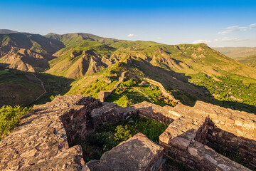 Naklejka na ściany i meble Panoramic view of the famous Smbataberd fortress in the Armenian Transcaucasia with gorgeous views of mountain valleys at golden sunset light