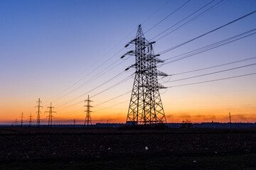 High voltage power line in a field at sunset