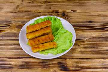 Baked fish sticks and lettuce leaves in a plate