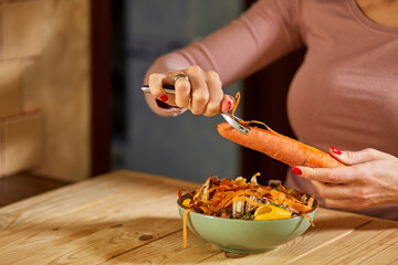 Women scraps peels carrots vegetable peeling, throws in compost bucket, organic composting