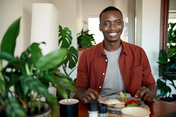 Smiling young African man eating breakfast at his dining table