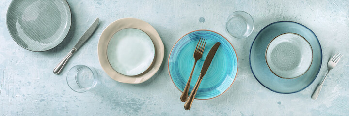 Modern tableware panorama, shot from the top. Dinnerware flat lay with a vibrant blue plate and...
