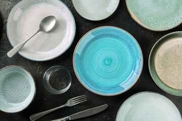 Modern tableware set with cutlery and a vibrant blue plate, overhead flat lay shot on a black slate...