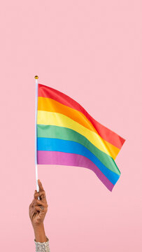 LGBTQ+ pride flag with woman&rsquo;s hand raising