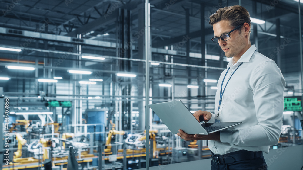 Poster handsome engineer in glasses and white shirt using laptop computer and looking out of the office at 