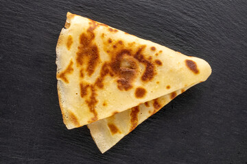 One sweet homemade pancake on a plate of slate, close-up, top view.