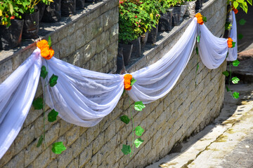 Stone wall decorated with marigold flower,flowers and white cloth.