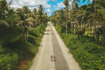 Fototapeta na wymiar Aerial drone view a Couple on the road with palm trees in Siargao, Philippines.