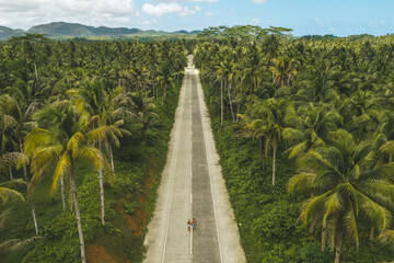 Aerial drone view a Couple on the road with palm trees in Siargao, Philippines.